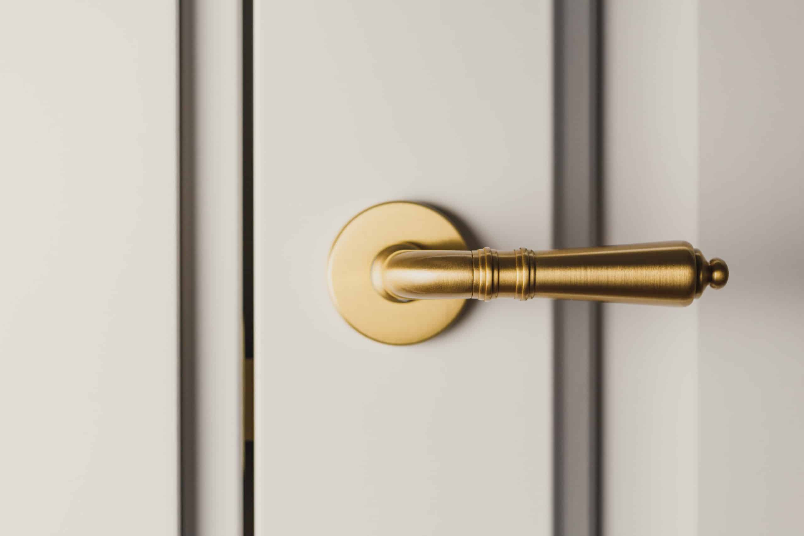 Brushed gold modern design in vintage style door handle on a white door.